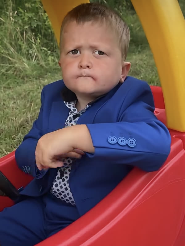 AI baby in a blue suit sitting in a toy car
