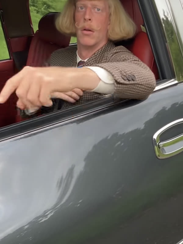 AI character Jean with a blonde bob pointing from a car window